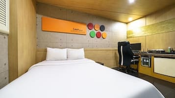 A hotel room with a bed, a desk, a chair, and a wall-mounted TV.