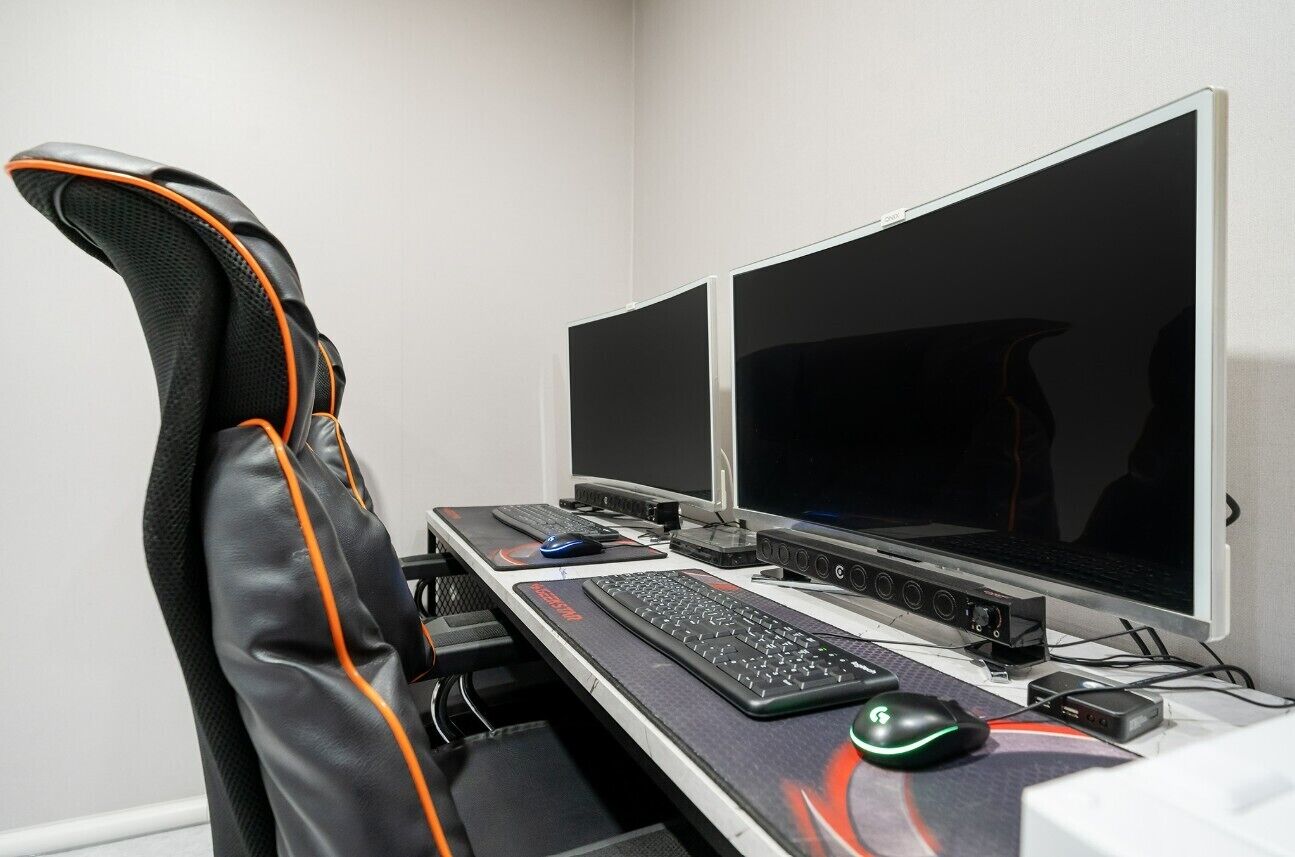 A gaming setup with a chair, two monitors, a keyboard, a mouse, and a mouse pad.