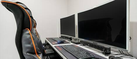 A gaming setup with a chair, two monitors, a keyboard, a mouse, and a mouse pad.