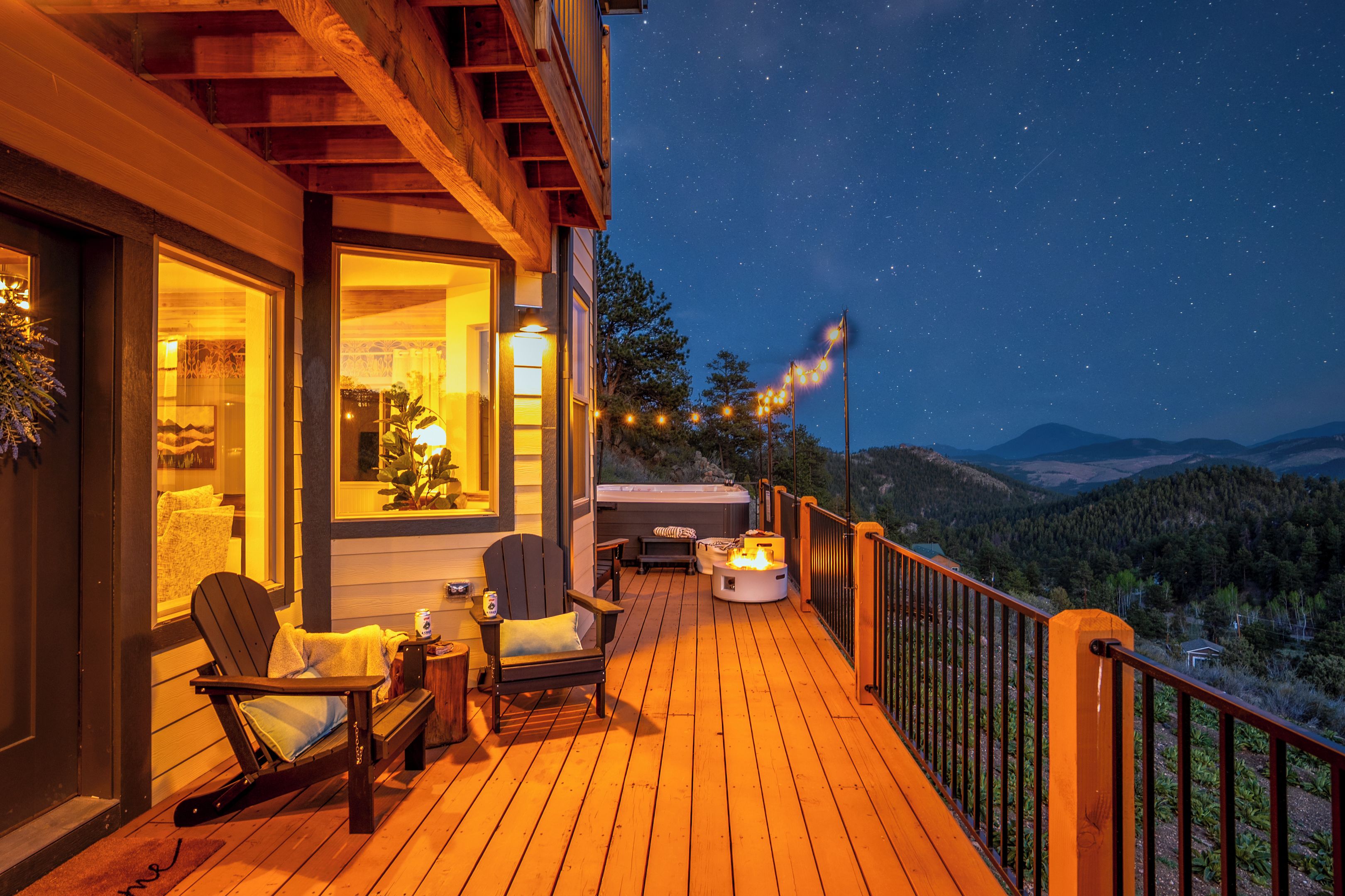 Un terrazzo in legno con posti a sedere all'aperto, una vasca idromassaggio e vista sulle montagne.
