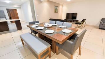 A dining area with a wooden table set for four, surrounded by grey upholstered chairs.