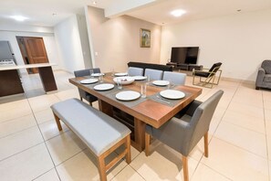 Een eetruimte met een houten tafel voor vier personen, omringd door grijze fauteuils.