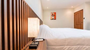 A hotel room with a bed, a bedside table with a lamp, a remote control, and a painting on the wall.