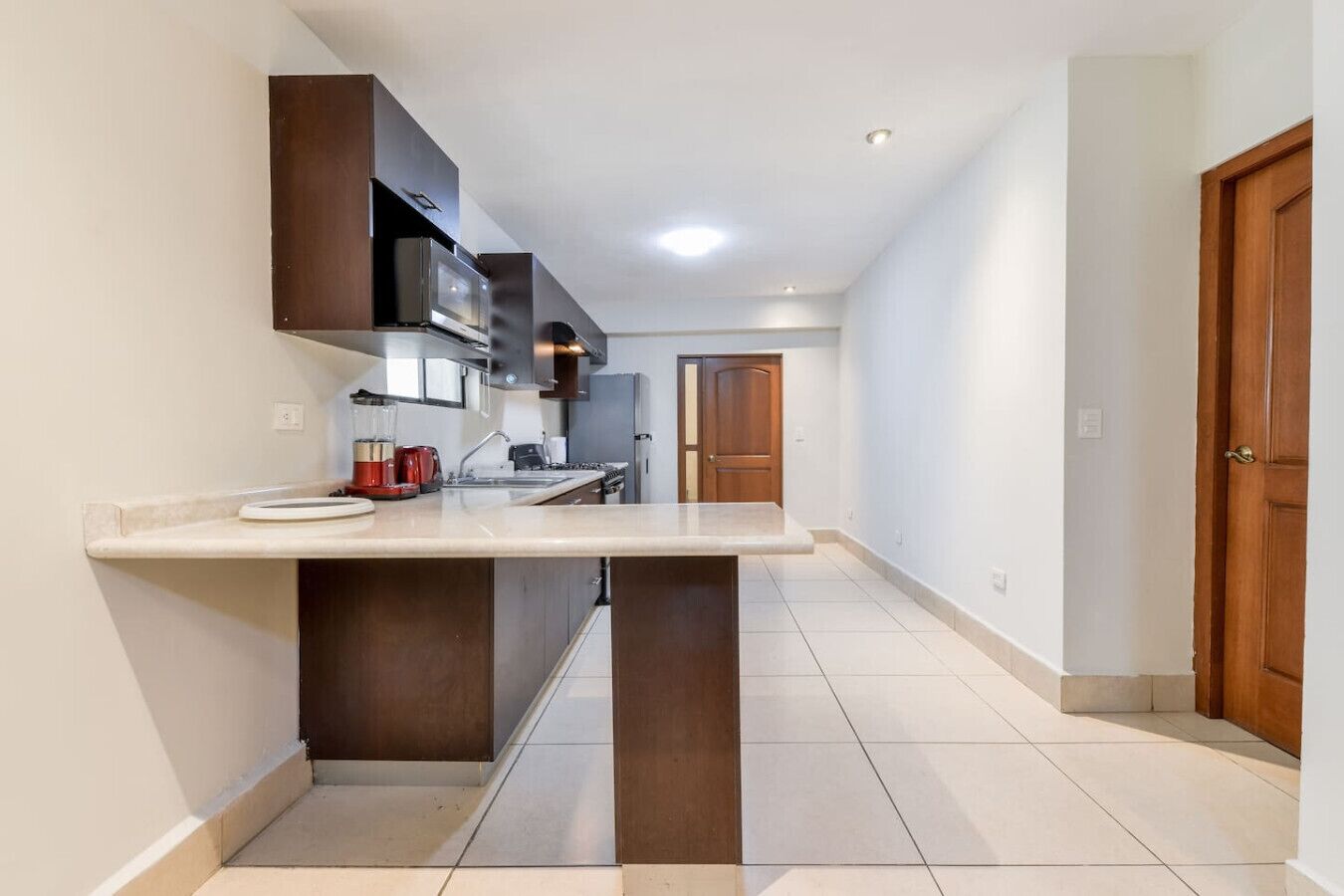 Een moderne keuken met een centraal eiland, ingebouwde apparatuur en een betegelde vloer.