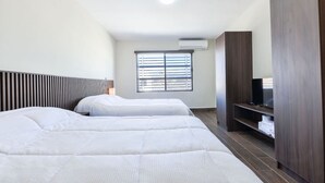 A hotel room with two beds, a TV, a wardrobe, and a window with blinds. - 1 King, 4 Double bed, 2 Sofa bed, 2 Parking, 12ppl (Monterrey)