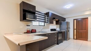 A modern kitchen with dark cabinetry, a built-in microwave, a gas stove, and a stainless steel refrigerator. - 1 King, 4 Double bed, 2 Sofa bed, 2 Parking, 12ppl (Monterrey)