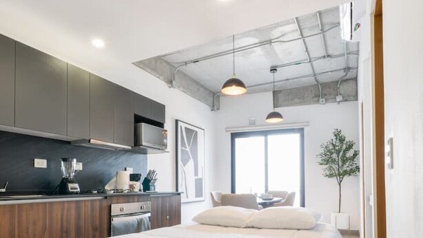 Un dormitorio moderno con una cama grande, una kitchenette y vistas al exterior.