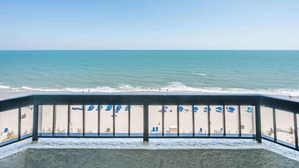 A balcony with a view of a beach and ocean. - Decorated Oceanfront  Condo with Amazing Heated Pool (Myrtle Beach)