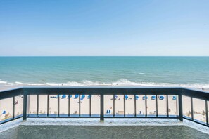 Een balkon met uitzicht op strand en zee.
