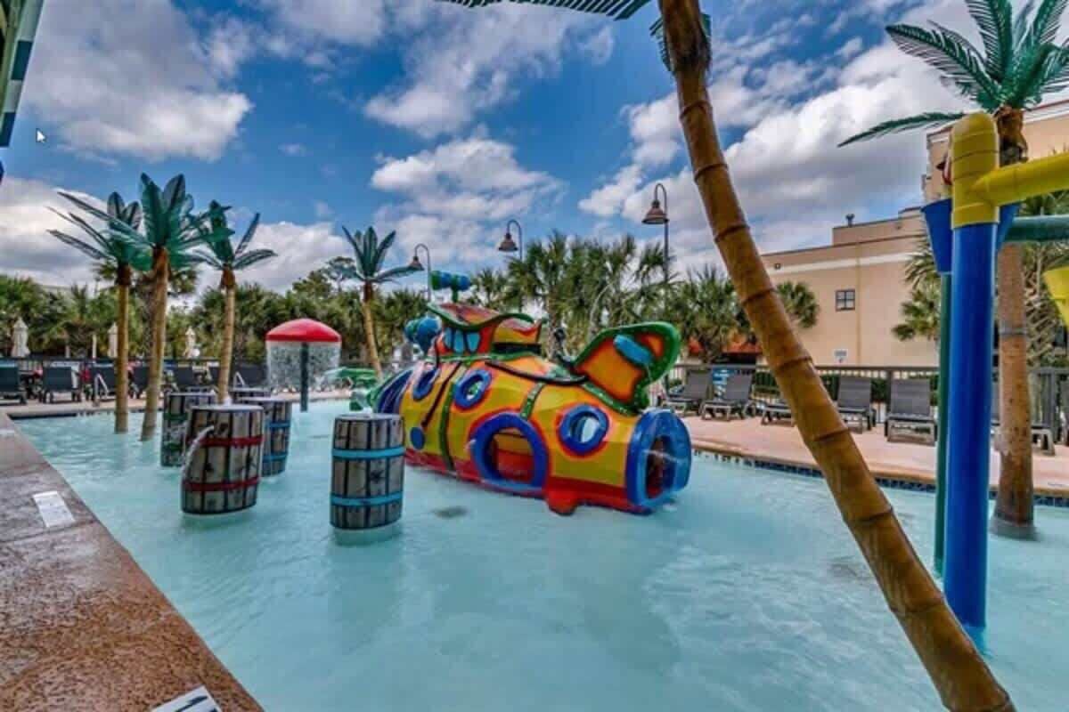 A water park with a colorful water slide and palm trees.