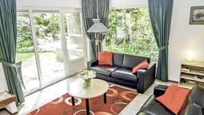A modern living room with a sofa, coffee table, and curtains. - Nice apartment in villa for 6 people with WIFI, TV, terrace and pets allowed (Lochem)