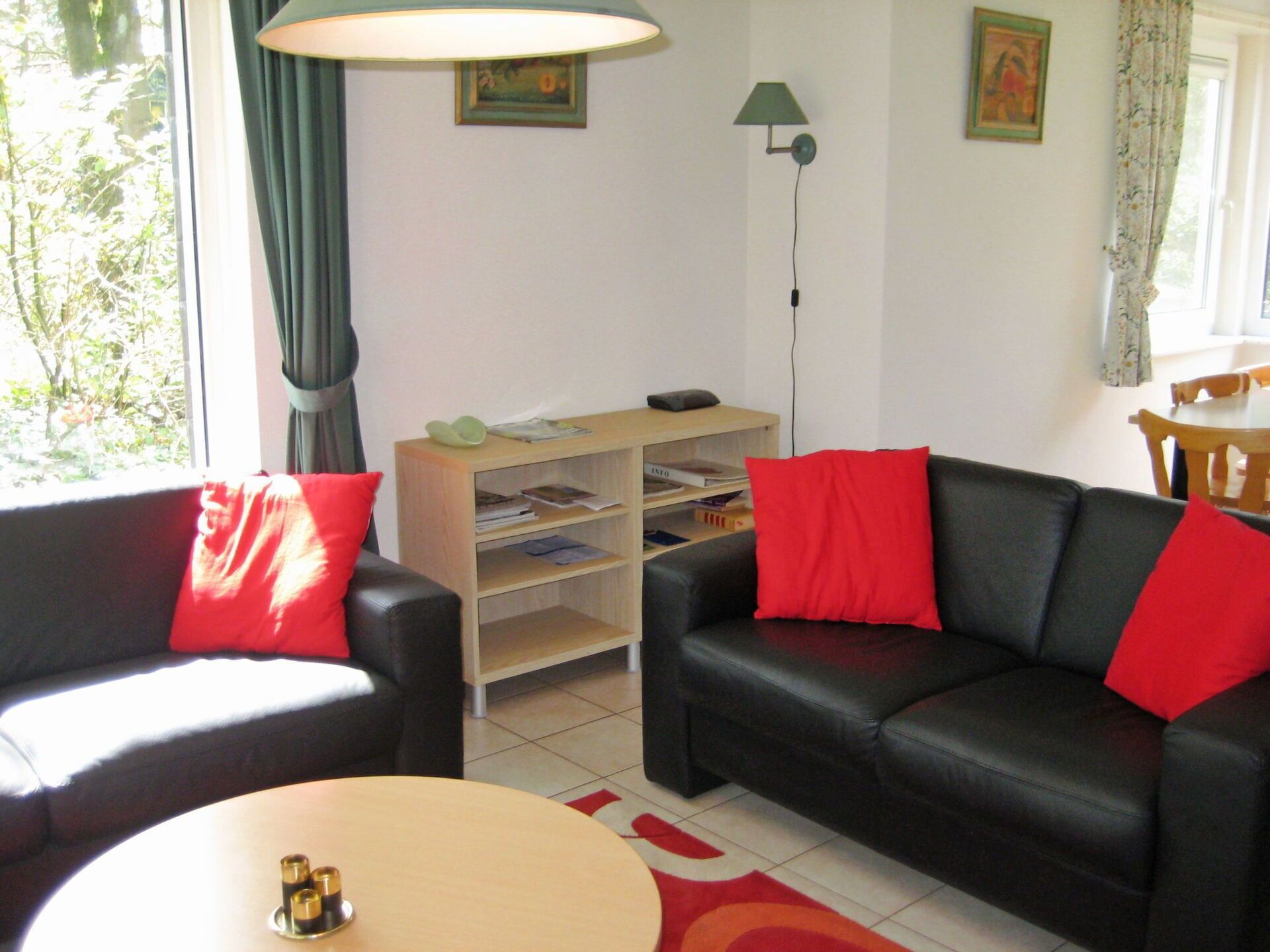 A living room with two black leather sofas, a wooden side table, a bookshelf, and a floor lamp.
