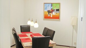 A dining area with a wooden table, red placemats, black chairs, and hanging pendant lights. - Nice apartment in villa for 6 people with WIFI, TV, terrace and pets allowed (Lochem)