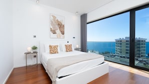 Ein modernes Schlafzimmer mit einem großen Bett, Blick auf die Stadt und einem Vorhangfenster.