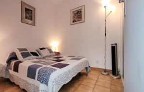 Ein Schlafzimmer mit einem Bett, zwei an der Wand befestigten Bildern, einer Nachttischlampe und einer Stehlampe.