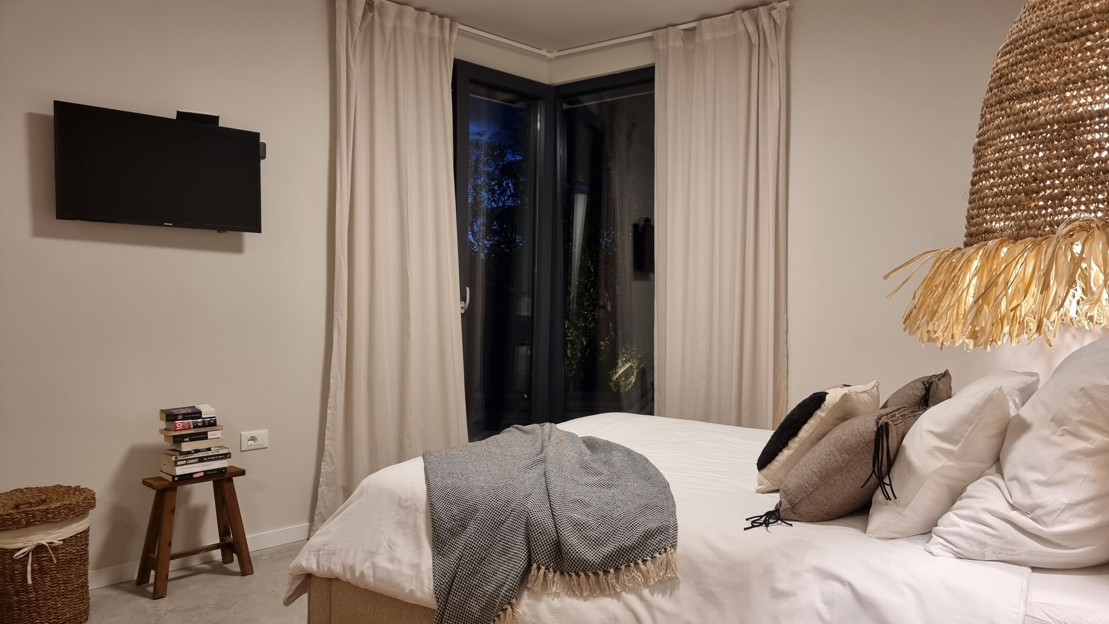 Une chambre à coucher avec un lit, un téléviseur fixé au mur et une vue sur l’extérieur par une porte.