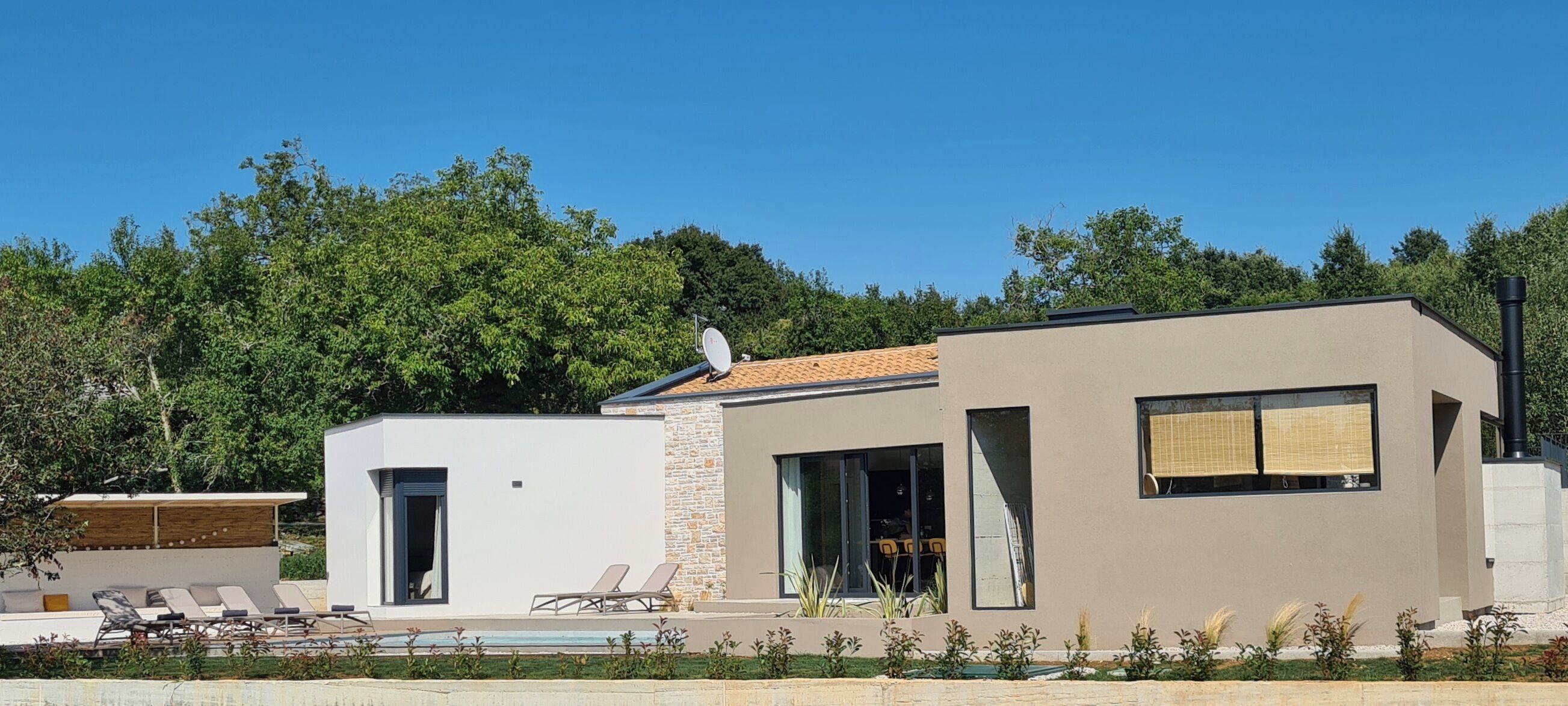 Una casa moderna de dues plantes amb una piscina, un porxo cobert i una finestra gran.
