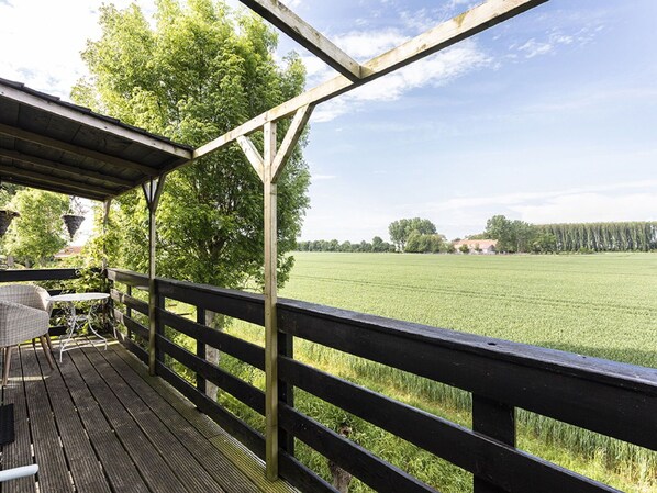 Un terrazzo in legno con vista su un prato verde e alberi.