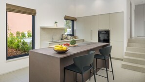 A modern kitchen with a central island, bar stools, and a view of greenery outside. - Villa La Mari (Istria - Poreč) (Poreč)