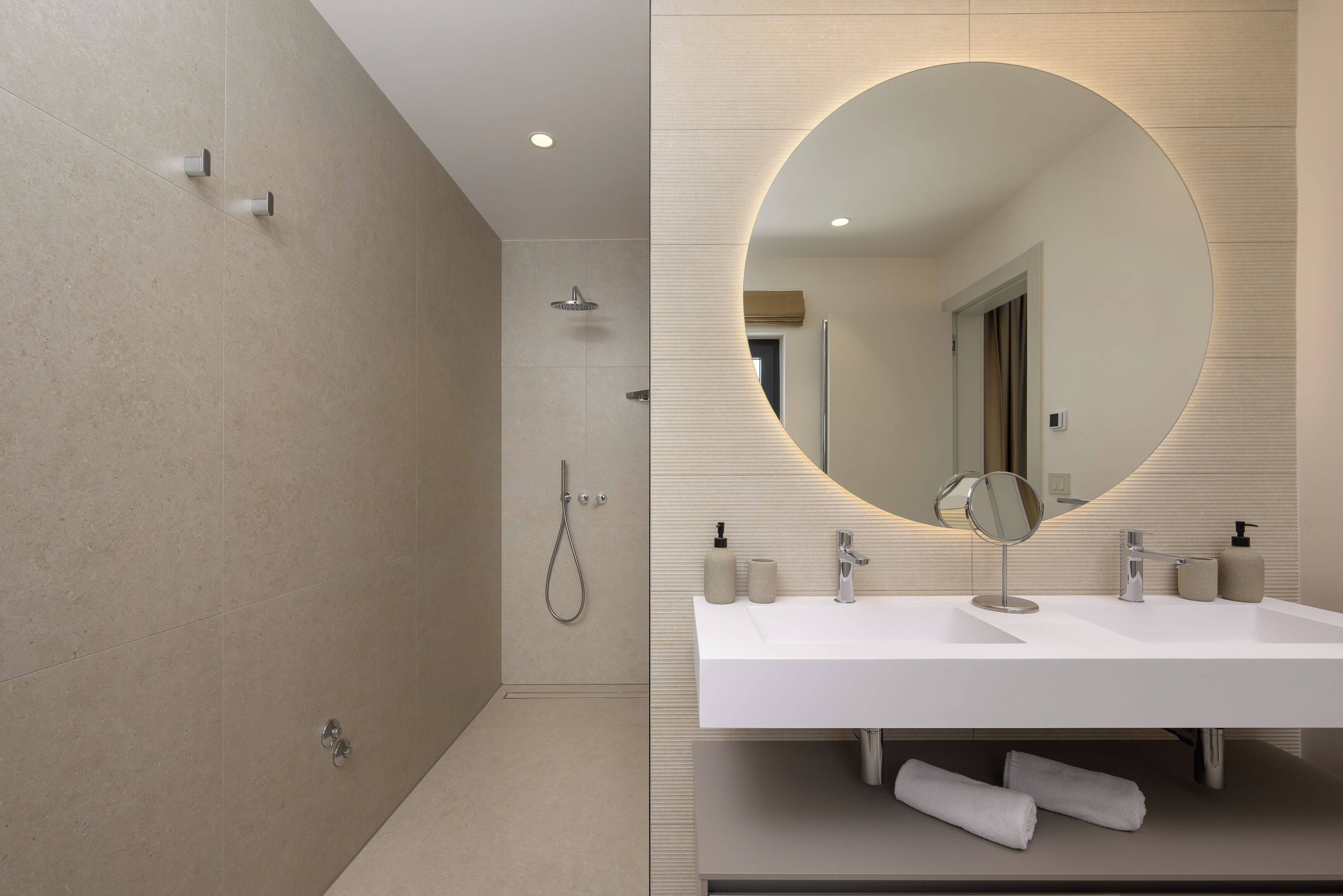 Une salle de bain moderne équipée d’une douche, d’un lavabo et d’un miroir.