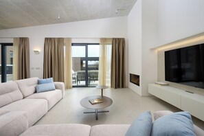 A modern living room with a sofa, a coffee table, a TV, and a sliding glass door leading to an outdoor area. - Villa La Mari (Istria - Poreč) (Poreč)
