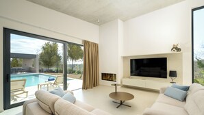 A modern living room with a large TV, a pool, and a sofa. - Villa La Mari (Istria - Poreč) (Poreč)