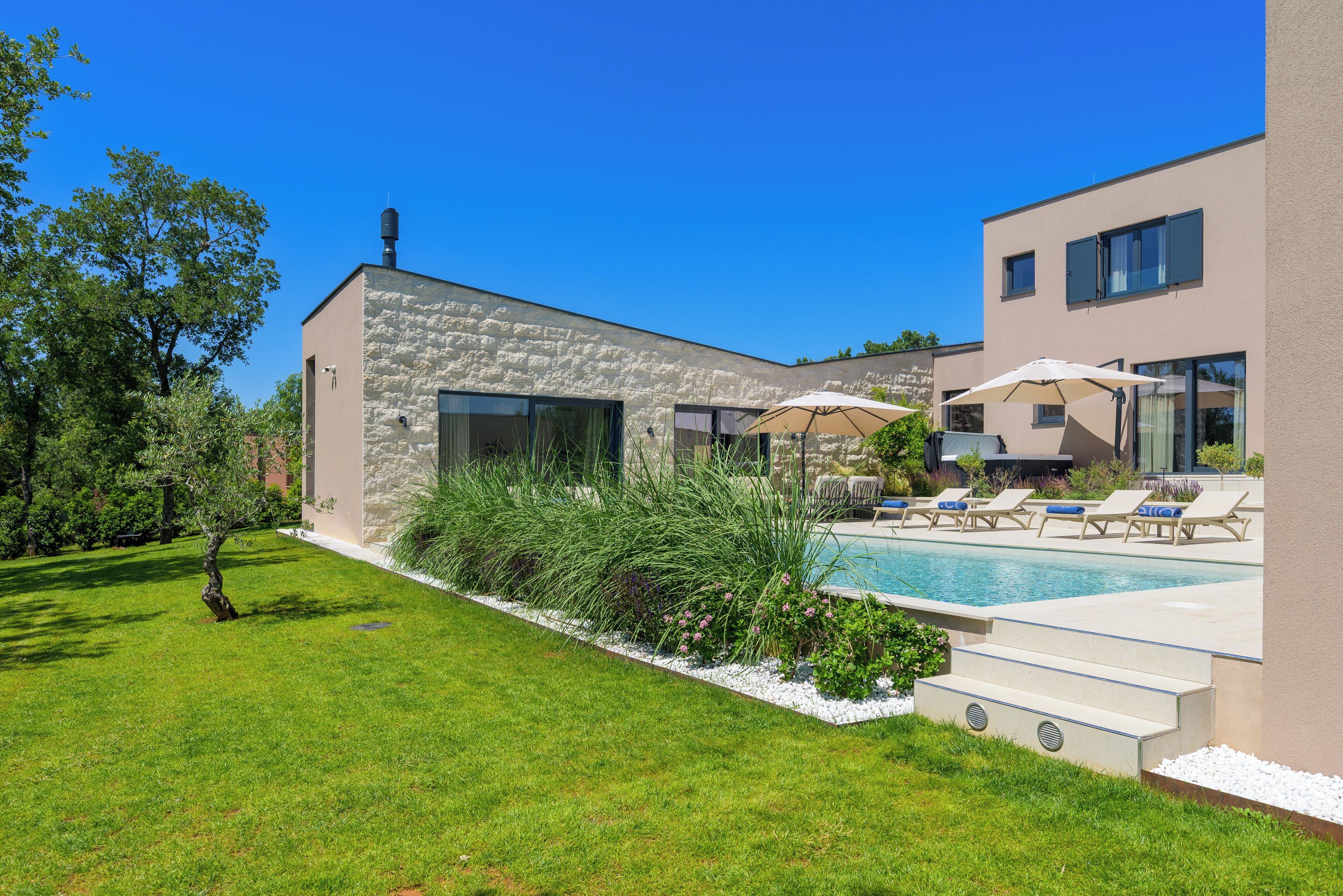 A modern house with a swimming pool, outdoor seating, and a well-maintained garden.