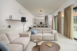 Ein modernes Wohnzimmer mit einer Couch, einem Couchtisch und einem Essbereich im Hintergrund.