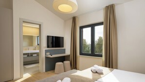 Una habitación de hotel moderna con cama, televisor, escritorio y ventana con cortinas.