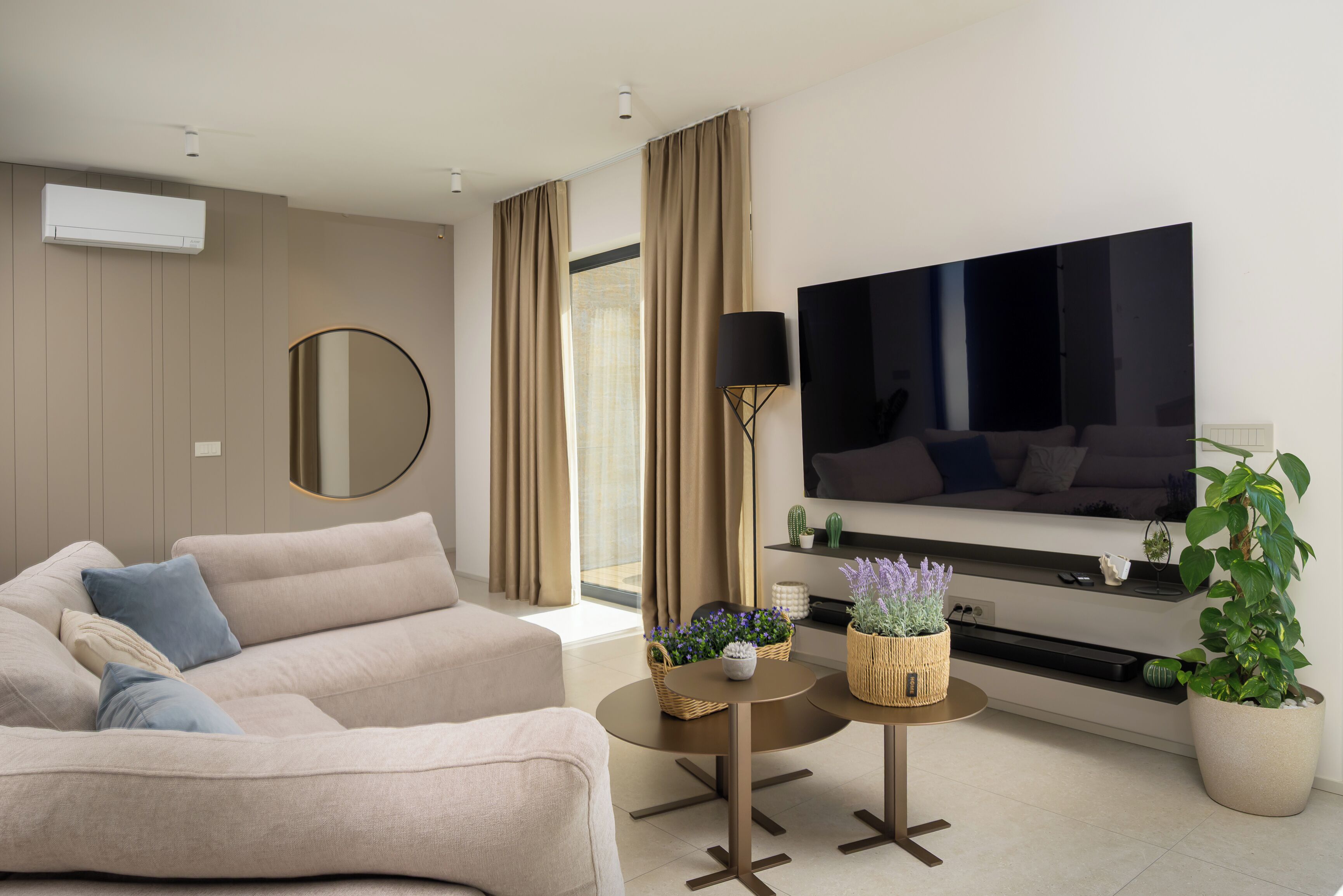 Ein modernes Wohnzimmer mit einer Couch, einem Flachbildfernseher, einem Couchtisch und einer Topfpflanze.