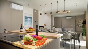 Una cucina moderna con un piano di lavoro in legno, un tagliere con verdure e un'area pranzo con tavolo e sedie.