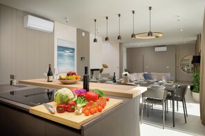 A modern kitchen with a wooden countertop, a cutting board with vegetables, and a dining area with a table and chairs. - Villa Sola (Istria - Poreč) (Poreč)