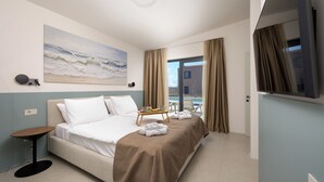 Una camera d'albergo con un letto, un quadro, un tavolo con asciugamani e vista sull'esterno.