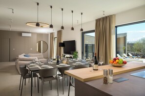 A modern dining area with a long table, chairs, and a fruit bowl. - Villa Sola (Istria - Poreč) (Poreč)