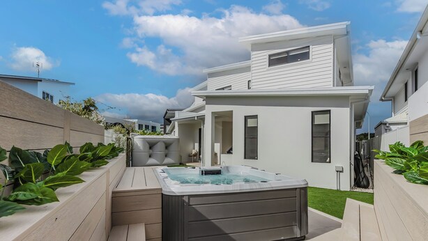 A modern house with a hot tub, a wooden deck, and a small garden. - Black Wattle Beach House (Casuarina)