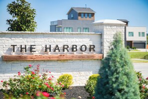 Une enseigne portant l’inscription « THE HARBOR », entourée de verdure et avec des bâtiments modernes en arrière-plan.