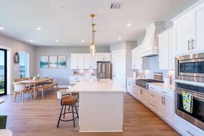 A modern kitchen with white cabinetry, stainless steel appliances, and a central island.