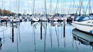 Un port esportiu amb nombroses embarcacions amarrades, aigua tranquil·la i un cel serè.