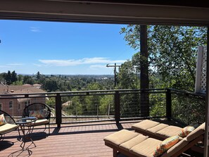 Ein Balkon mit Blick auf eine Stadtlandschaft, einem Tisch und zwei Liegestühlen.