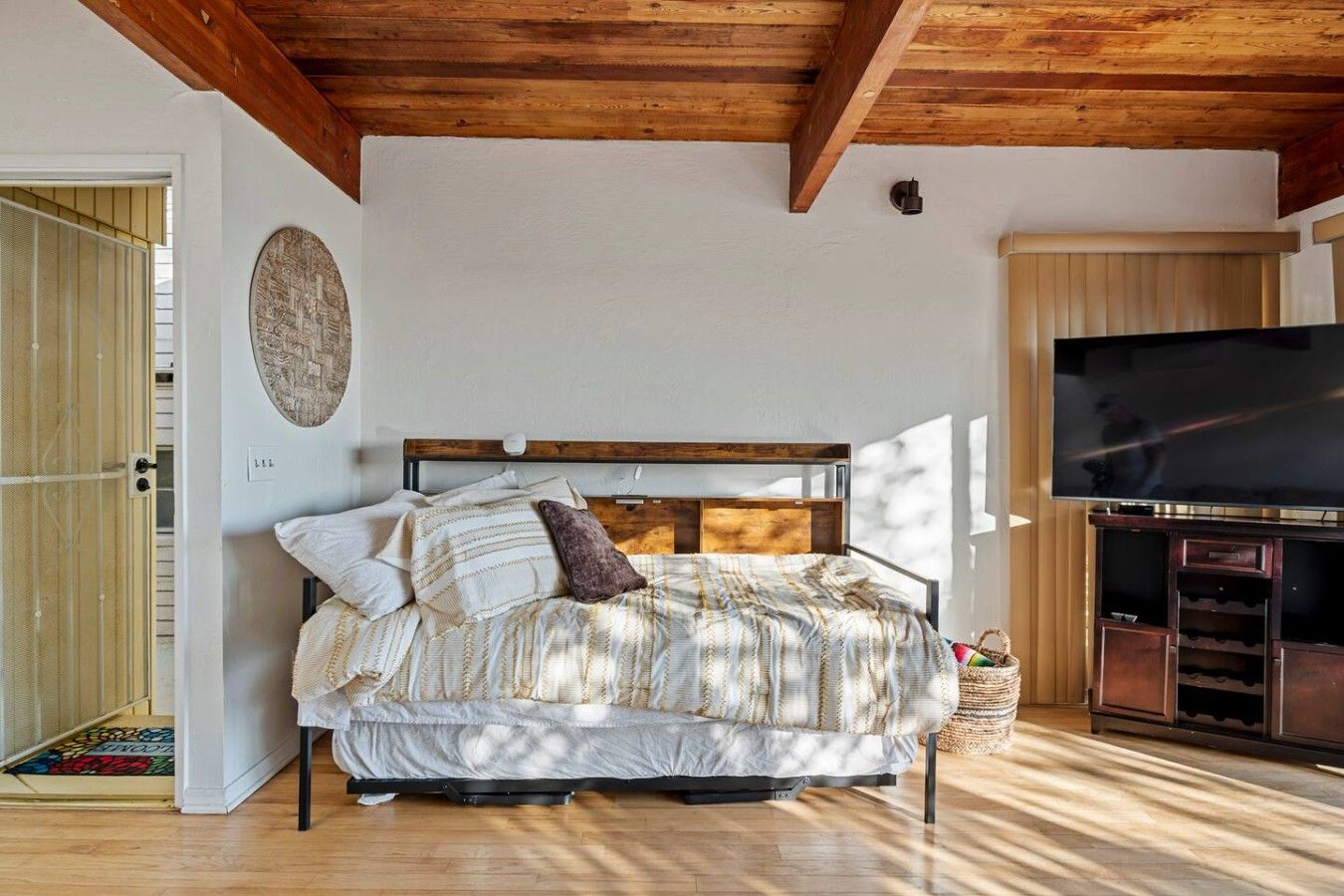 Ein Schlafzimmer mit einem Bett, einem Fernseher und einer Holzbalkendecke.