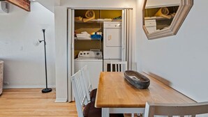 Et kompakt køkken med en indbygget vaskemaskine, et spisebord med stole og et spejl på væggen.