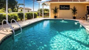 Uma piscina com um letreiro 'Welcome', área de estar externa e vista da região ao redor.