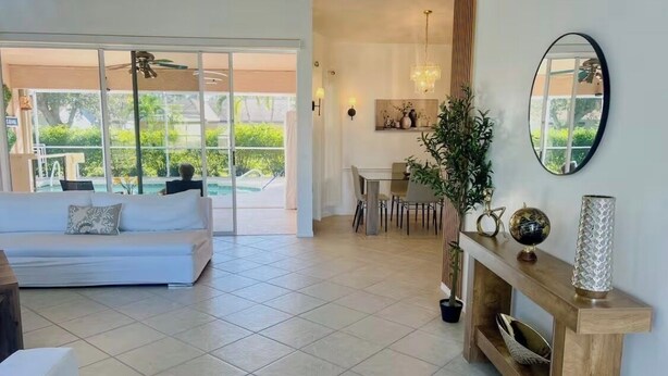 Ampla sala de estar com sofá, mesa de jantar e vista para a piscina externa.