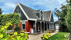 Une maison traditionnelle avec un porche, une allée en gravier et un jardin.