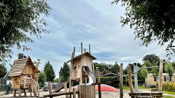 Une aire de jeux dotée de structures en bois, notamment d’un toboggan et d’échelles d’escalade.