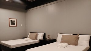 A room with two single beds, each with a pillow and a small bedside table. - Roccia Transient  (San Fernando)