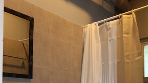 A bathroom with a sink, toilet, and shower curtain. - Roccia Transient  (San Fernando)
