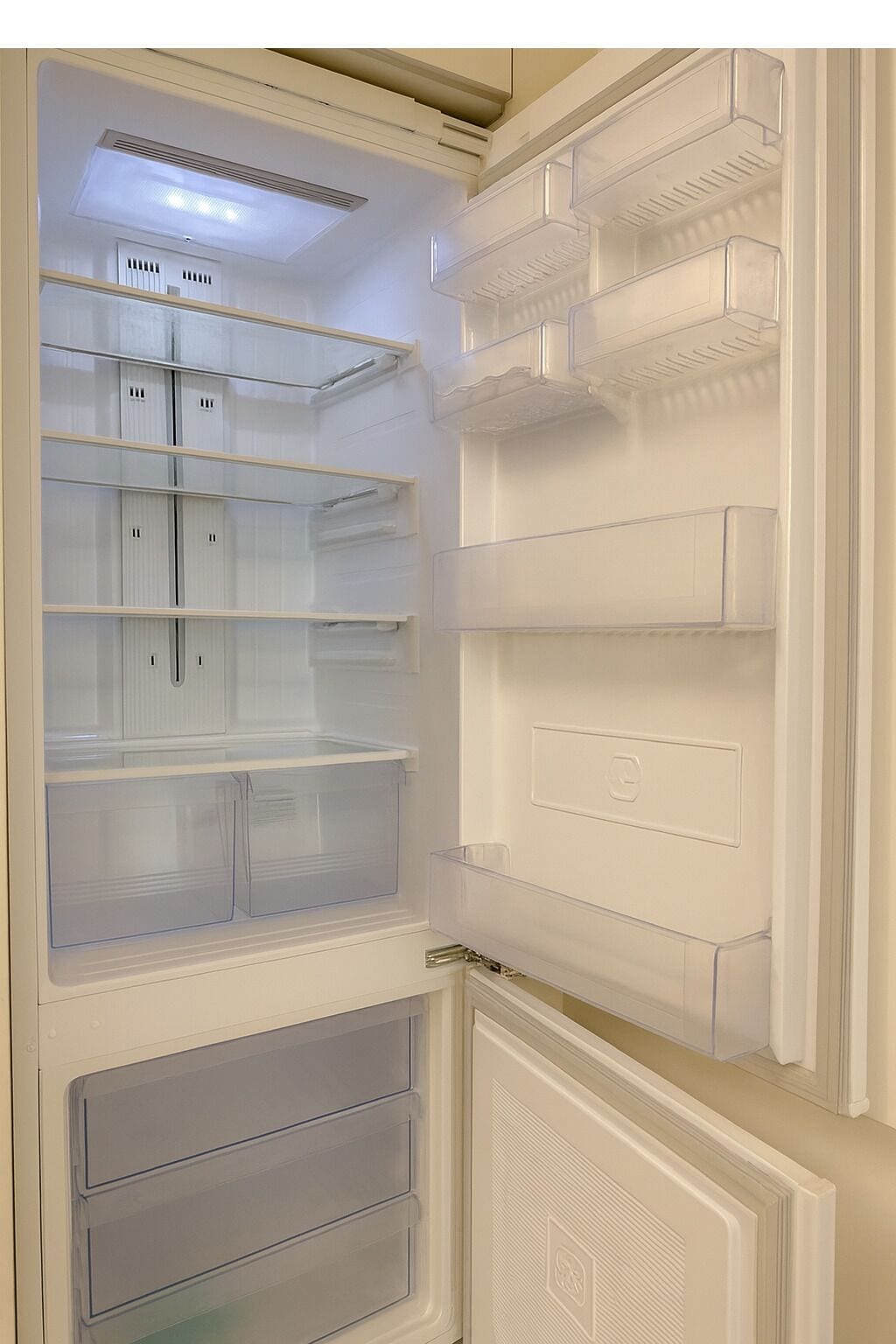 An open refrigerator with multiple shelves and drawers, a control panel, and a freezer compartment.