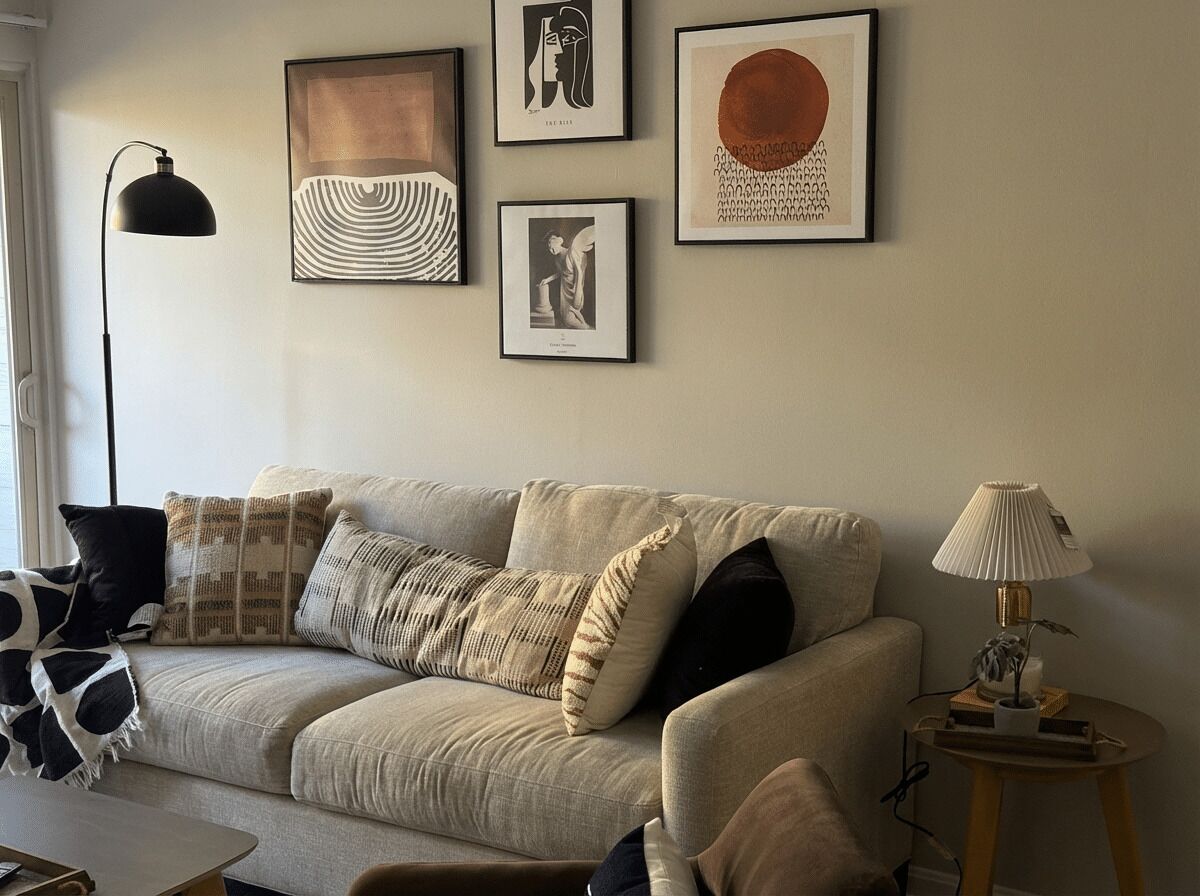 A living room with a sofa, a lamp, and framed artwork on the wall.