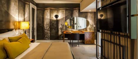 A modern bedroom with a bed, desk, and a large mirror.